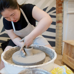 A person is using a pottery wheel to shape clay into a bowl.