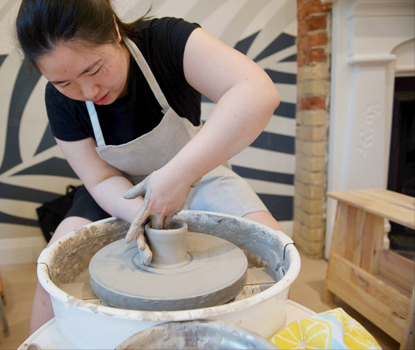 A person is using a pottery wheel to shape clay into a bowl.